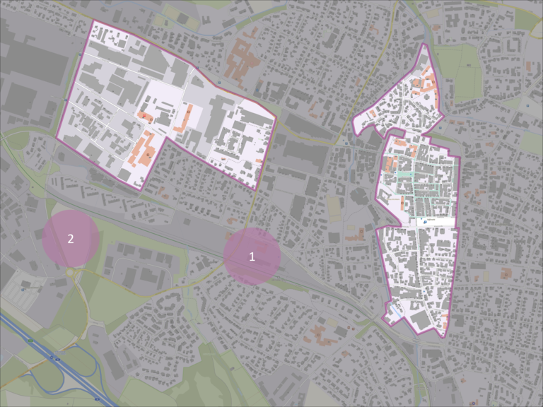 Die Karte zeigt ein urbanes Gebiet mit zwei markierten Zonen in Rosa, nummeriert als 1 und 2, die potenzielle Heizzentralen darstellen, sowie zwei größeren, weiß umrandeten Gebiete, die die Innenstadt und das Gewerbegebiet darstellen.